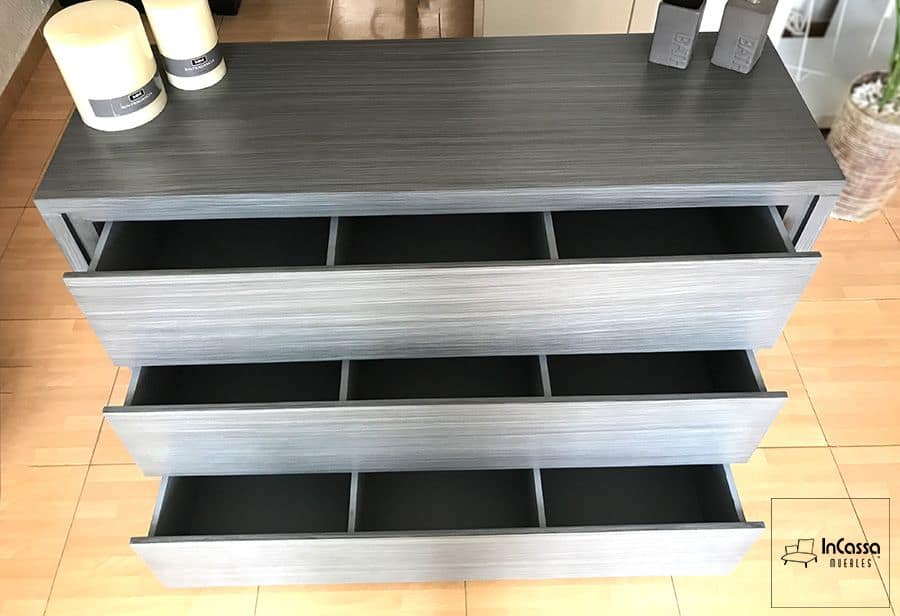 Vista superior del tocador en color gris cenizo oscuro con sus cajones abiertos, destacando sus divisiones internas que facilitan la organización eficiente de ropa y accesorios en la recámara.