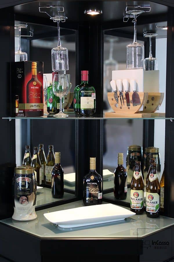 En esta imagen se destacan los estantes de vidrio del esquinero cantina, diseñados para exhibir con estilo tus botellas y accesorios de bar. Los soportes para copas invertidas optimizan el espacio, mientras que la iluminación LED resalta los detalles, creando un ambiente sofisticado. Un mueble en acabado chocolate completo que combina practicidad y estética para complementar cualquier espacio.