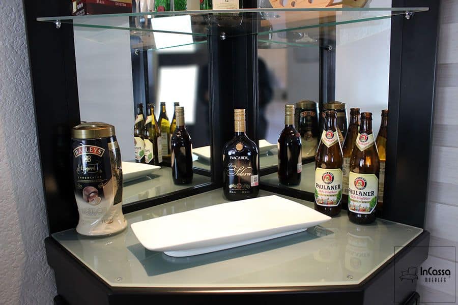 En esta toma se destaca la superficie de cristal templado del esquinero de bar chocolate, diseñada para exhibir bebidas y utensilios con elegancia. Su acabado reflectante, combinado con el espejo posterior, amplifica la luz y el espacio visual, creando un ambiente sofisticado ideal para cualquier reunión social.