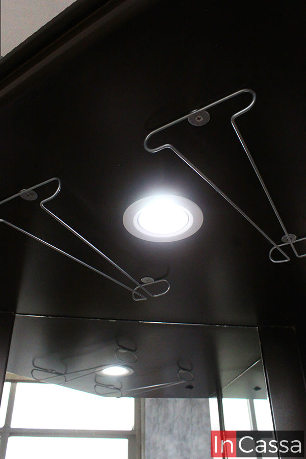 En primer plano, la Cantina Modelo LILIAN en acabado tabaco destaca por sus colgadores metálicos para copas y su iluminación integrada, detalles que realzan la presentación de tu cristalería. Un diseño elegante que combina funcionalidad y sofisticación para cualquier espacio.