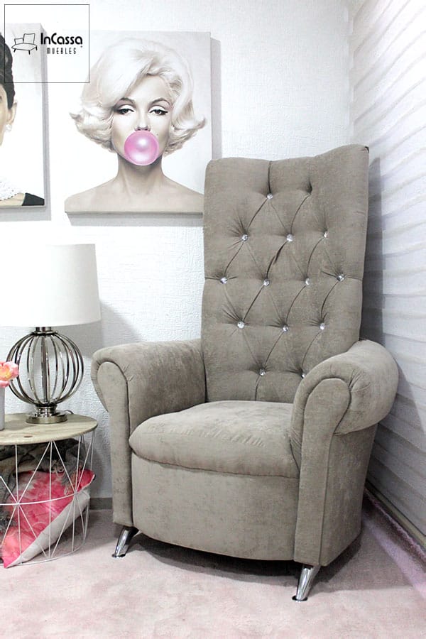 Este sillón tapizado en suave tela suede gris perla destaca por su respaldo alto con detalles capitoné y botones decorativos. Sus brazos curvos y patas metálicas inclinadas aportan un estilo sofisticado, ideal para realzar cualquier espacio con un toque de distinción.