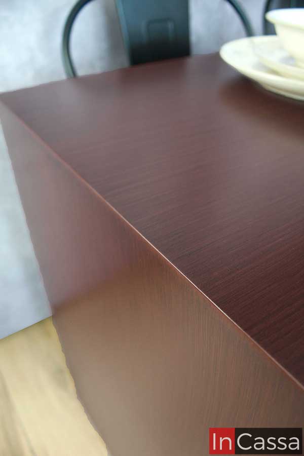 En esta imagen se aprecia de cerca la textura de la mesa, donde su acabado en tabaco resalta una superficie suave y resistente, perfecta para el uso diario y fácil de limpiar.