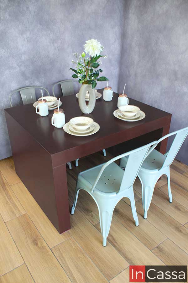 La mesa se presenta con sillas metálicas en un tono gris claro, ofreciendo una alternativa de color que ilumina el espacio y brinda versatilidad al diseño del comedor.