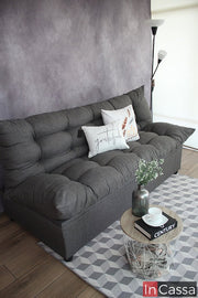 Una toma un poco más lateral del sofá cama en tela lino mouse, en la que se puede observar mas a detalle la construcción de su base además del acabado capitoneado presente en el respaldo y el asiento.