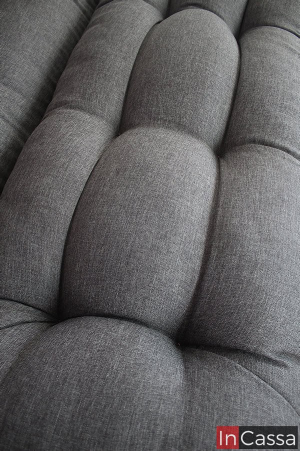 La foto nos enseña una toma cercana del asiento del sofá cama, en la que se puede apreciar de mejor manera los detalles capitoneados del tapizado así como la textura de la tela lino mouse.