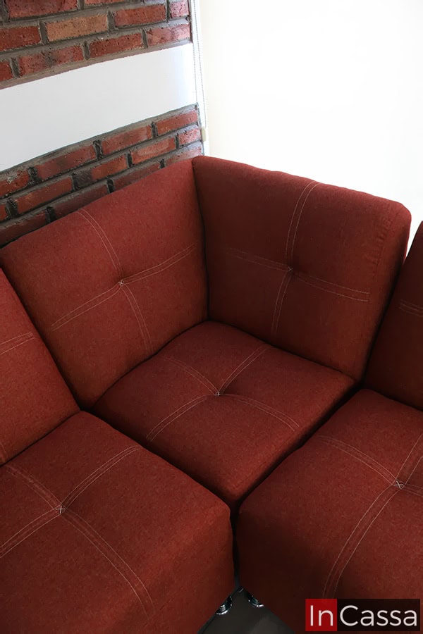 La imagen muestra un detalle superior de la esquina de la Sala Esquinera Modelo Londres, tapizada en pliana color cobre. Se aprecian las costuras decorativas en contraste que forman cuadros elegantes, junto al respaldo y asiento acolchados que realzan el diseño moderno y cómodo del conjunto.