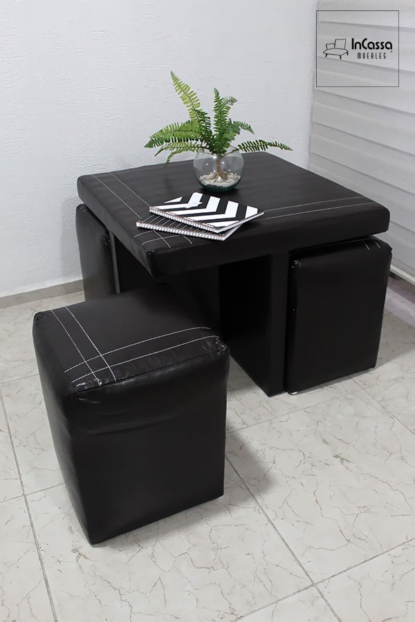 En esta toma se observa cómo los taburetes encajan perfectamente bajo la mesa; todos tapizados en tacto piel negro, optimizando el espacio. Este diseño versátil es ideal para departamentos o áreas de tamaño reducido, sin comprometer el estilo.