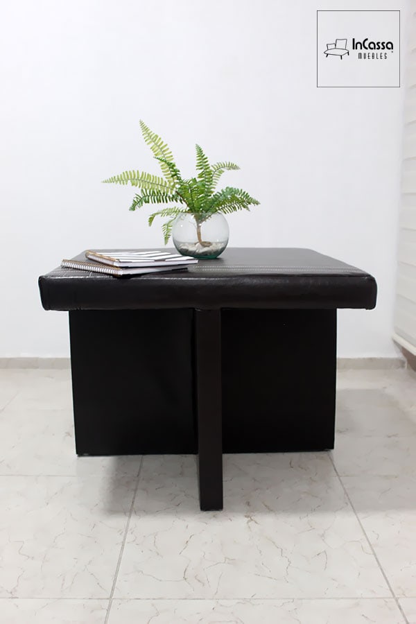 La toma presenta un enfoque lateral de la mesa Luarca, enfatizando la calidad de sus acabados. El contraste de las costuras blancas sobre el tacto piel negra añade un toque sofisticado a este diseño compacto.