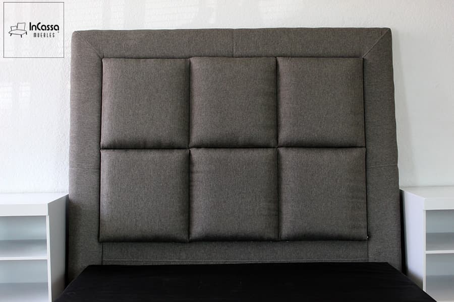 Se presenta una vista frontal cerrada de la cabecera tapizada en lino mouse con diseño de seis cuadros acolchados. A ambos lados, los burós blancos contrastan con elegancia, resaltando la simetría y el estilo moderno del conjunto.