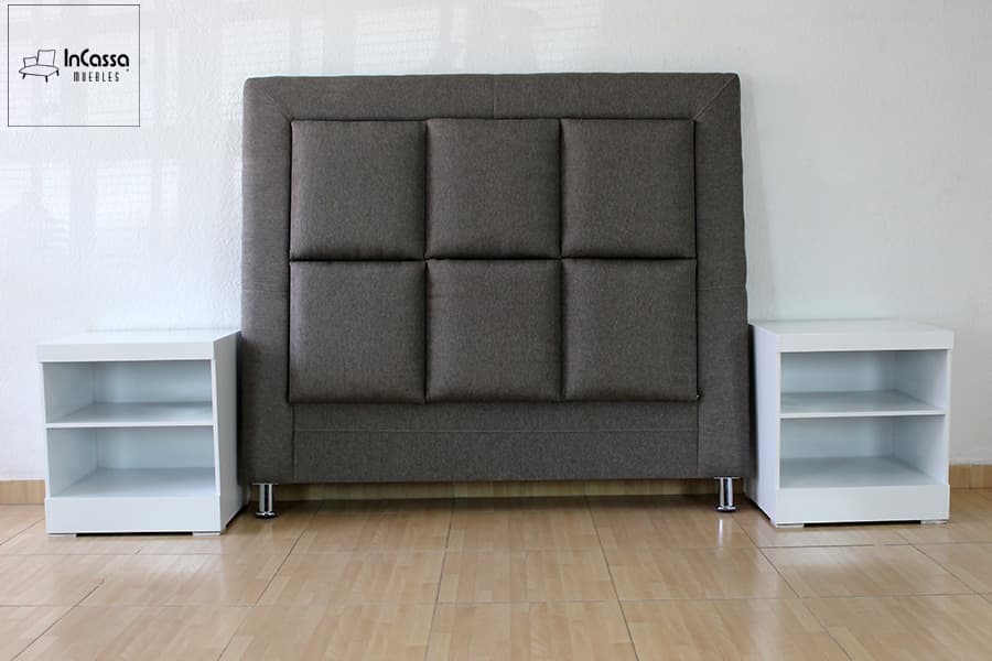 En esta imagen se aprecia una vista frontal de la cabecera tapizada en lino mouse con diseño acolchado en cuadros simétricos, acompañada por dos burós blancos de líneas rectas. El conjunto, sin la base de cama, resalta por su elegancia y contraste moderno.