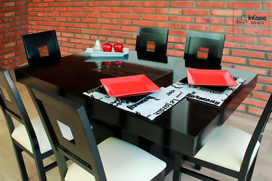 La fotografía presenta una toma lateral del Antecomedor Modelo MADRID, donde resalta su cubierta con arenero central de cristal y acabado en color chocolate brillante. Las sillas de respaldo cuadrado y asientos tapizados en suede tono hueso aportan contraste y elegancia, creando un ambiente moderno y acogedor.