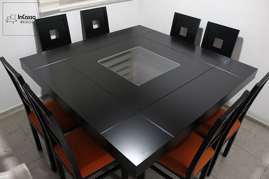 La imagen muestra una vista superior del Antecomedor Modelo MADRID en color chocolate, destacando su cubierta cuadrada con arenero central de cristal que aporta modernidad y luminosidad al diseño. Las sillas con asientos tapizados en suede naranja añaden un contraste cálido y contemporáneo al conjunto.