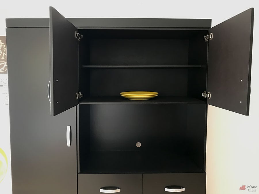 La imagen muestra el módulo superior de la Alacena para Microondas MÁLAGA en color chocolate mate, con ambas puertas abiertas revelando dos repisas internas. En la repisa inferior destaca un plato amarillo como acento decorativo, creando contraste con el fondo oscuro.