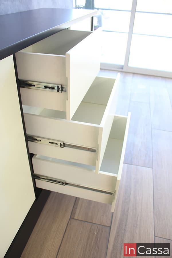 La toma se enfoca en los cajones del bufetero, destacando los rieles metálicos integrados a cada compartimento para su apertura y cierre. El interior de cada cajón es bastante amplio y con buena profundidad, sus bordes laterales cuentan con largos orificios que sirven como jaladeras, además de que la estructura completa de cada cajón es de color blanco.