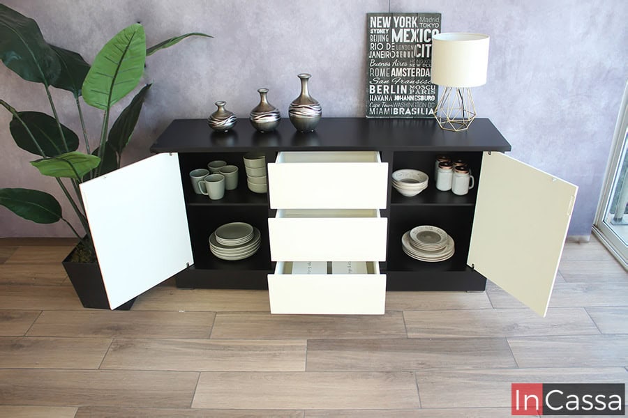 El bufetero es presentado con sus puertas y cajones abiertos, dejando a la vista los espacios con los que cuenta, los cuales son decorados con algunas vajillas a fin de ejemplificar las capacidades de cada espacio. Como podemos ver la estructura total del mueble es de color negro, mientras que sus puertas y cajones son de color blanco completo.