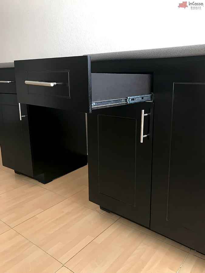 La imagen muestra el cajón extensible del módulo inferior de la cocina MCALLEN para estufa en color chocolate, con correderas metálicas de extensión que garantizan un deslizamiento suave y resistente. La cubierta en formaica granito purpina y las jaladeras metálicas rectas aportan un estilo contemporáneo y funcional.