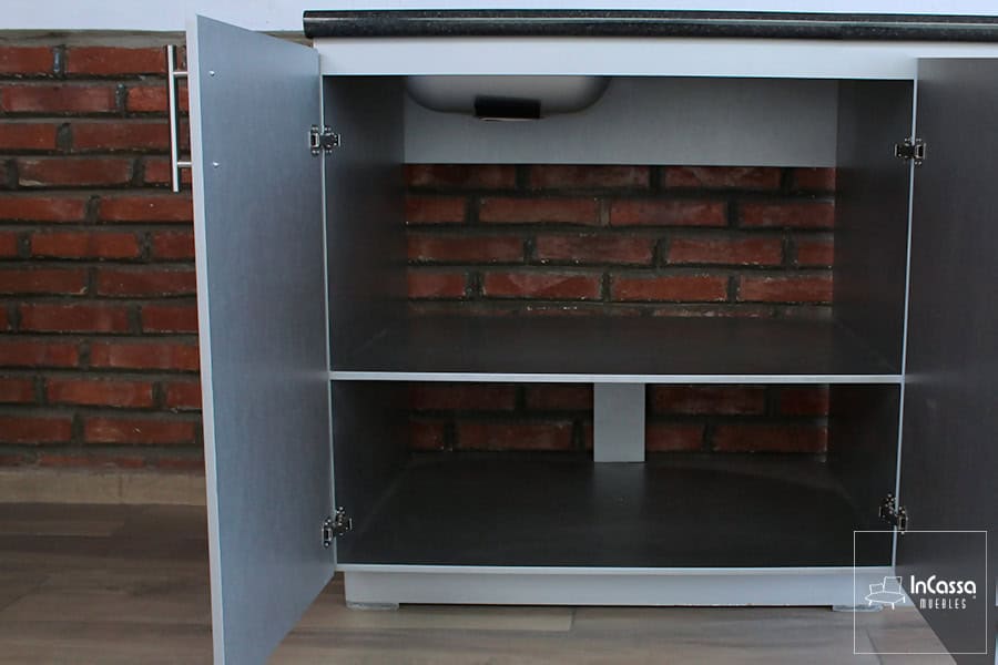 Una toma del módulo inferior del modelo MEDELLÍN para parrilla en color silver con ambas puertas abiertas revela dos niveles amplios de almacenamiento. Se observa la parte inferior de la tarja montada, ideal para organizar productos de limpieza u otros utensilios de cocina.