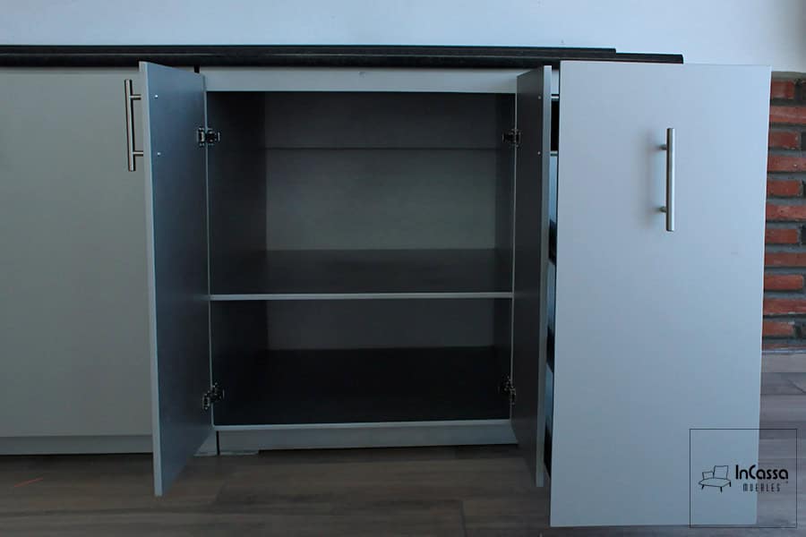 Esta imagen muestra el la sección lateral del módulo inferior del modelo MEDELLÍN para parrilla en color silver, con puertas abiertas que revelan un espacioso interior dividido por una repisa fija. Ideal para almacenar utensilios grandes o productos de limpieza, ofrece un acceso cómodo y una excelente organización.