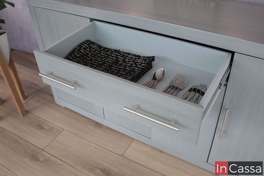 En esta fotografía se aprecia un acercamiento al cajón superior del Bufetero Vintage Modelo MISSISSIPPI, mostrando su interior espacioso en tono gris claro. El ángulo evidencia la amplitud del compartimento y la suavidad del deslizamiento, ideal para cubiertos, servilletas o utensilios diarios. Las jaladeras metálicas al frente realzan su diseño moderno mientras el acabado gris cenizo claro mantiene una estética elegante y uniforme.