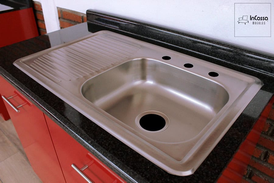 La fotografía destaca la tarja de acero inoxidable de la Cocina Integral MONTEVIDEO de 2.90m para ESTUFA en color rojo vivo, integrada sobre cubierta de formaica en estilo mármol negro que aporta resistencia, funcionalidad y un elegante contraste moderno.