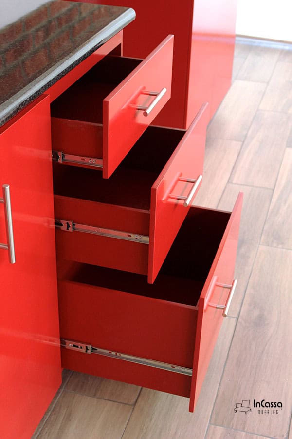 La fotografía destaca los cajones inferiores de la Cocina Integral MONTEVIDEO de 2.90m para ESTUFA en color rojo vivo, equipados con correderas metálicas de extensión y jaladeras modernas que brindan practicidad, suavidad y un estilo contemporáneo.