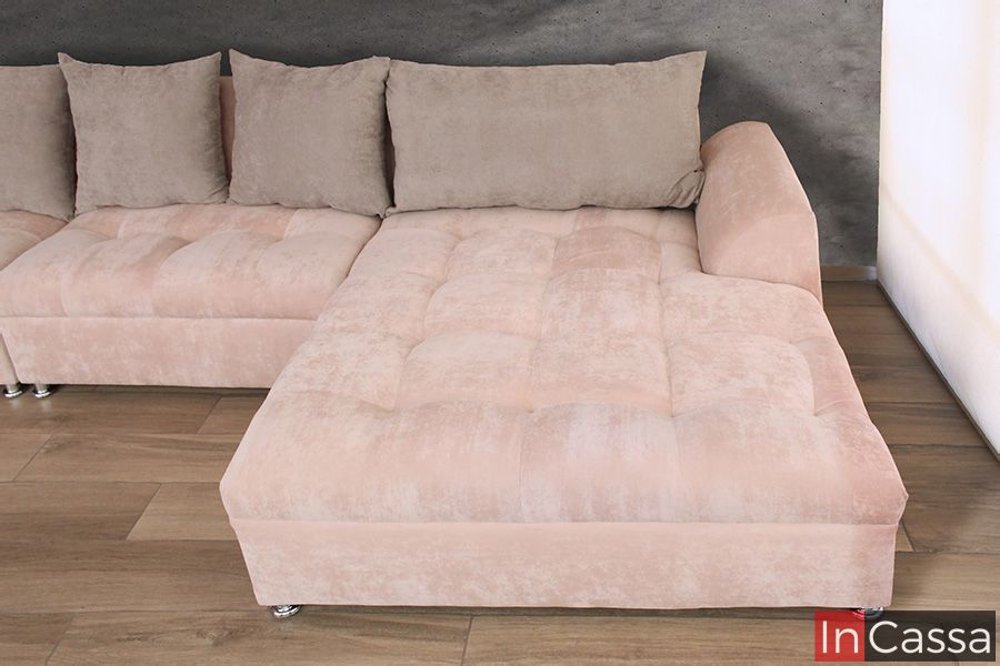 Una toma superior en perspectiva muestra el chaise longue de la sala en tapiz suede rosa palo, con respaldo acolchonado y brazo lateral. El diseño amplio y cómodo invita al descanso en un ambiente moderno y sofisticado.