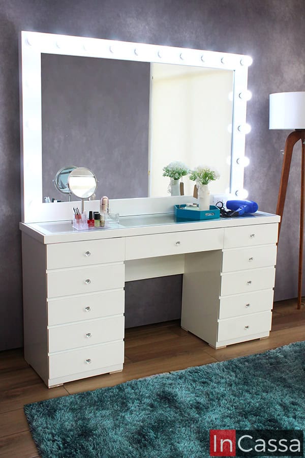 La foto presenta el tocador Mykonos en acabado blanco, acompañado de un amplio espejo rodeado de 18 luces LED. Sus 11 cajones, con elegantes jaladeras estilo diamante, brindan gran capacidad de organización y un toque sofisticado para realzar el espacio.