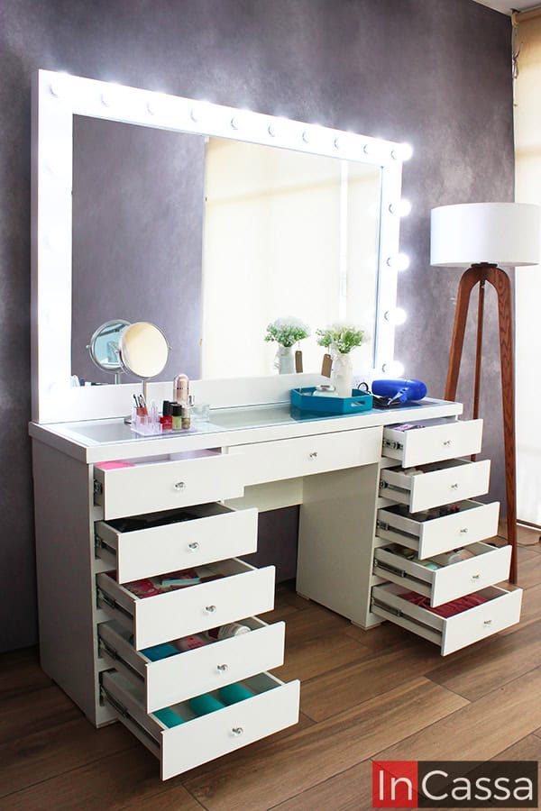 Una toma lateral del tocador Mykonos en color blanco exhibe sus 11 cajones abiertos, perfectos para almacenar maquillaje y accesorios. Las jaladeras estilo diamante resaltan su diseño elegante, mientras el espejo iluminado con 18 focos LED aporta luminosidad y modernidad.