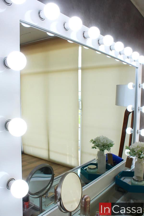 Primer plano del espejo del Tocador Mykonos, rodeado por 18 focos LED que proporcionan una iluminación uniforme y profesional. El marco blanco resalta la luz, creando un ambiente ideal para maquillaje y arreglo personal.