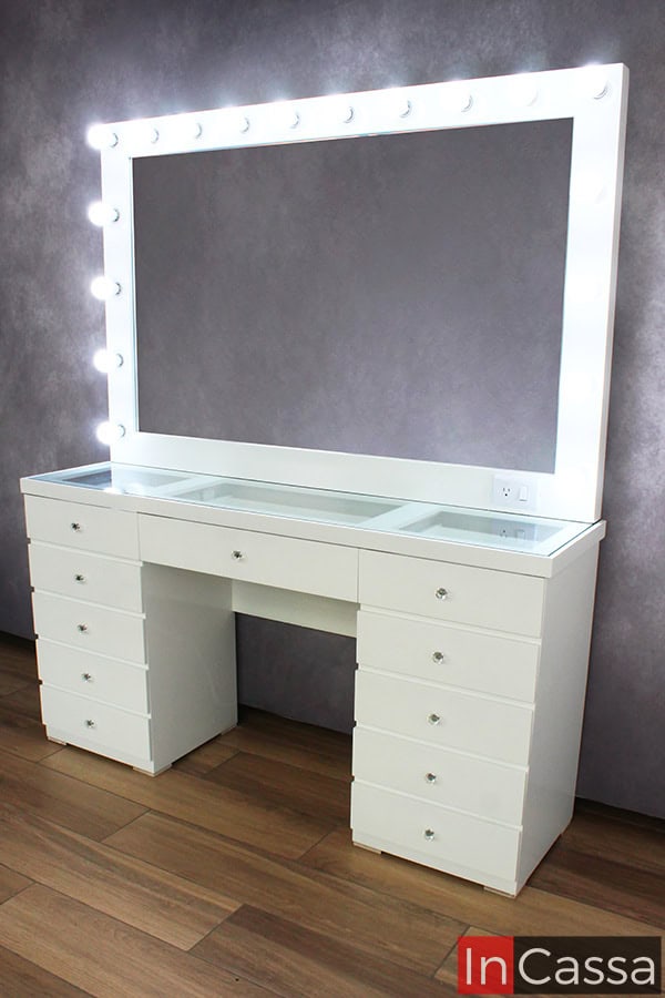 Fotografía lateral del Tocador Mykonos en acabado blanco brillante, destacando su espejo de gran tamaño con 18 focos LED y sus 11 cajones con jaladeras estilo diamante. Su diseño elegante y funcional lo convierte en el mueble ideal para un espacio moderno y sofisticado.