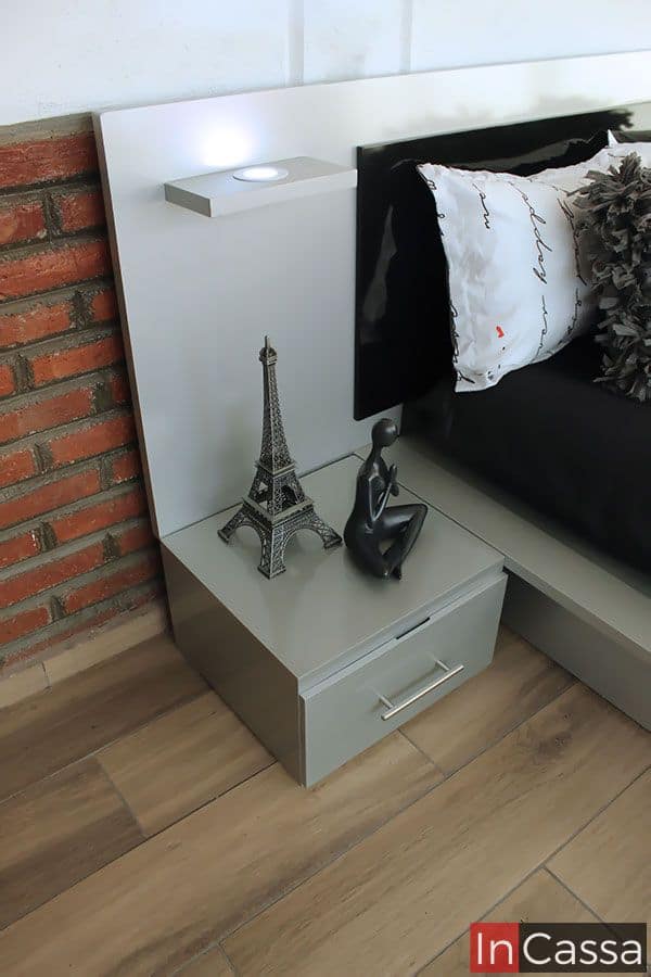 Buró gris con cajón, parte de un conjunto de cama moderna. Incluye iluminación LED integrada en la cabecera y detalles decorativos como una figura y una réplica de la Torre Eiffel. Ideal para un dormitorio elegante y contemporáneo, combinando funcionalidad y estilo.