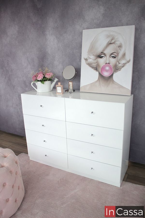 Foto del tocador de ocho cajones tomada desde una toma lateral, en la que se muestra un poco más de la estructura del mueble, la cuál es visiblemente blanca en su totalidad.