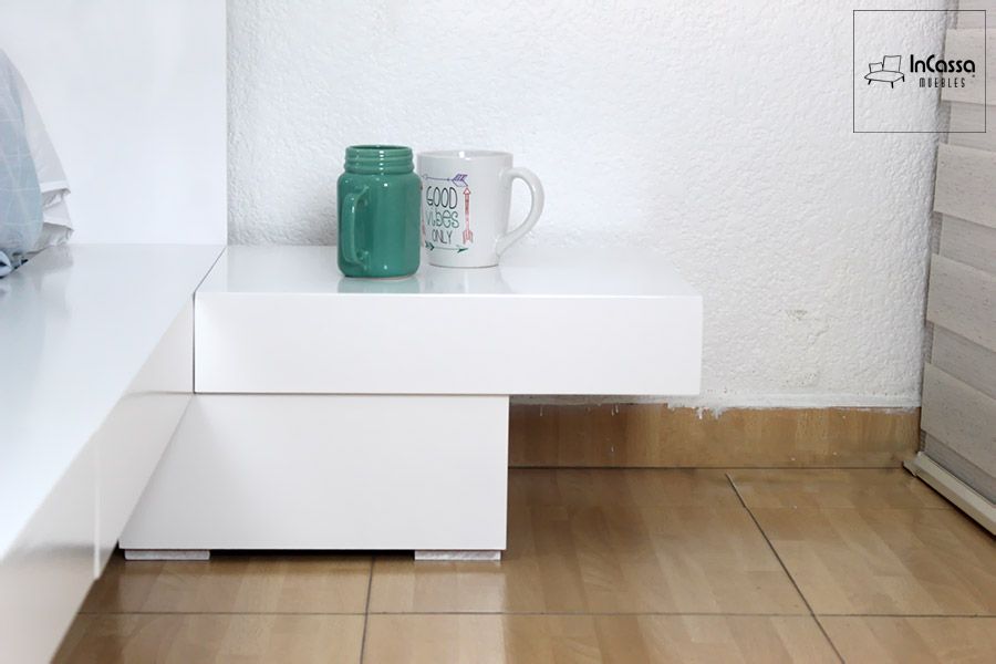 Este buró de líneas limpias y acabado blanco brillante forma parte del conjunto de cama tipo plataforma. Su diseño moderno y simétrico ofrece una superficie útil para objetos personales, manteniendo la estética minimalista y funcional del dormitorio.