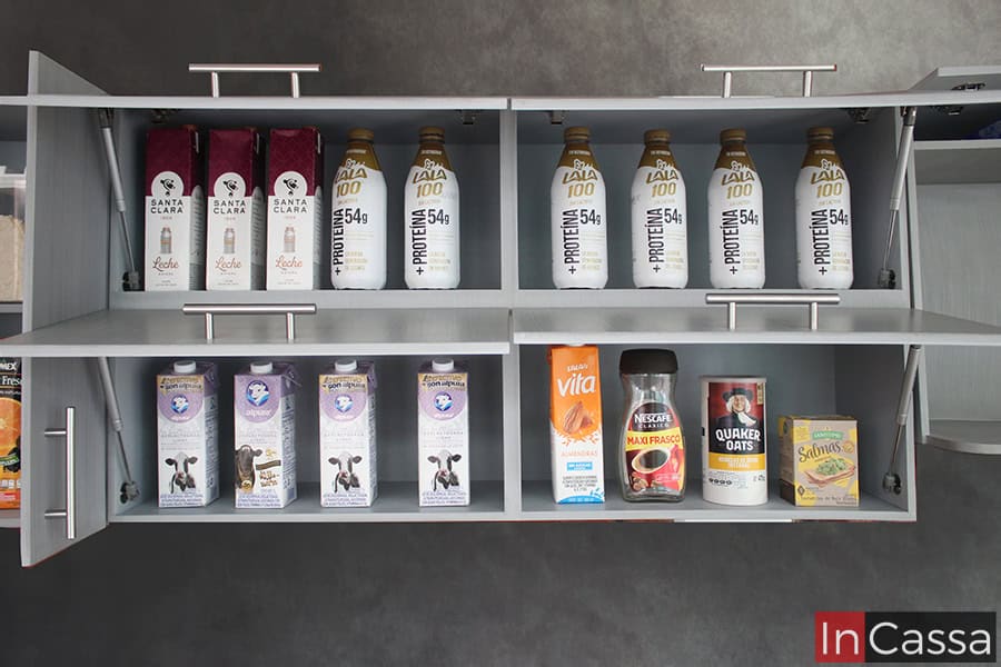 Una imagen que resalta los compartimentos interiores de la alacena superior de la cocina. Mostrando cuatro amplios espacios, cada uno con su propia puerta con pistones neumáticos para una apertura y cierre vertical. También puede apreciarse las jaladeras de barra T integradas a las puertas, y el acabado gris cenizo claro de los interiores, el mismo que puede verse en la totalidad de la cocina.