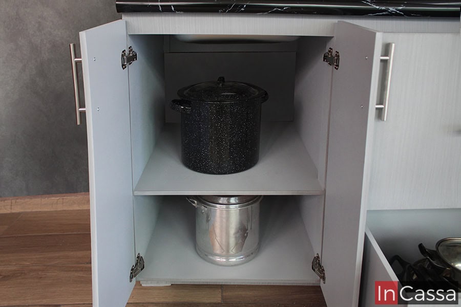 Vemos la parte inferior de la sección de tarja del módulo inferior, el cual cuenta con dos compartimentos lo suficientemente amplios como para almacenar grandes ollas. El espacio es dividido por un entrepaño horizontal, y tiene un acabado gris cenizo claro, el mismo que puede observarse el toda la cocina.