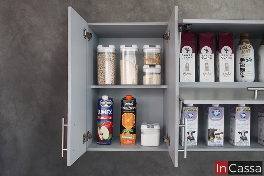 La imagen proporciona una vista cercana del módulo sobre tarja, presentado con sus puertas abiertas dejando visibles sus dos compartimentos divididos por un entrepaño horizontal. El módulo mantiene el mismo acabado gris cenizo claro tanto en sus partes interiores como en las exteriores.