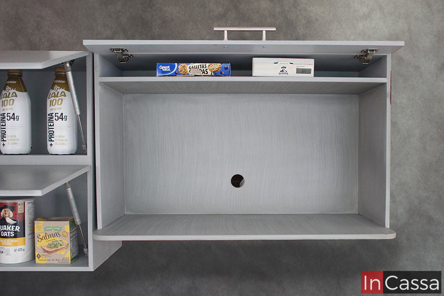 La foto destaca el mueble sobre campana, el cual cuenta con un amplio espacio para microondas y un pequeño compartimento adicional en su parte superior. La totalidad del módulo mantiene un acabado gris cenizo claro, el cuál puede verse incluso en el interior del compartimento superior.