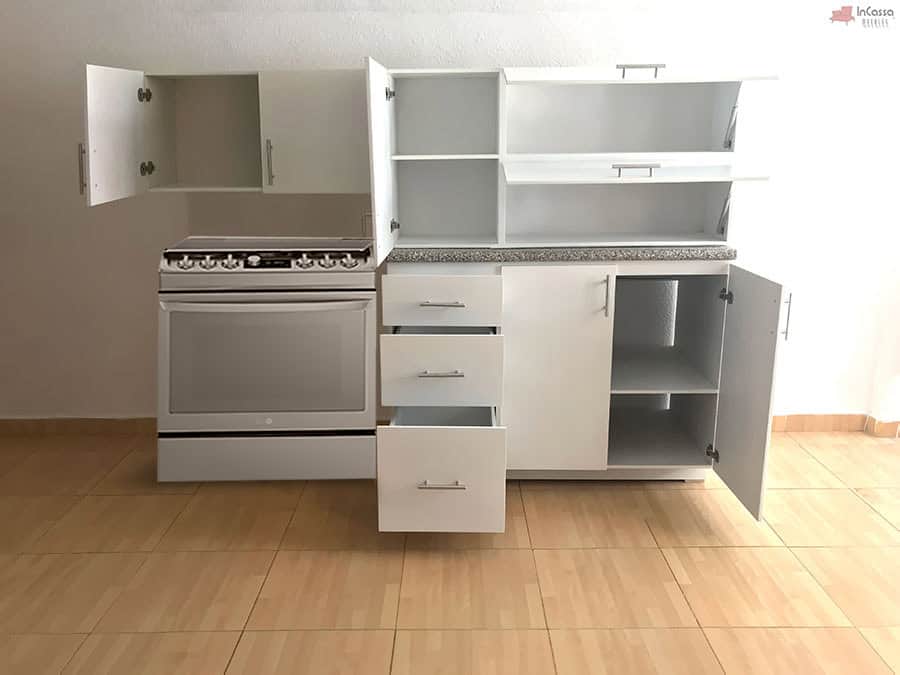 La imagen presenta una vista frontal completamente abierta de la Cocina Integral NEVADA de 2 m en color blanco, mostrando a detalle su capacidad interna. Se observan tres cajones deslizables, alacenas superiores divididas en amplios compartimentos, y el módulo inferior con puertas abiertas y repisas internas. La cubierta de formaica estilo granito purpina añade un acabado moderno y resistente.