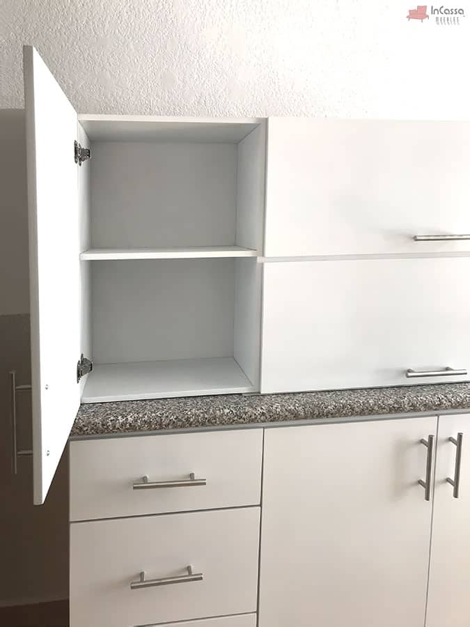 La foto presenta una toma lateral de la alacena superior de la Cocina Integral NEVADA de 2 metros en acabado blanco, mostrando una puerta abierta que revela dos compartimentos amplios y bien distribuidos. Se aprecia el tono uniforme del MDF chileno, las bisagras metálicas internas y, en la parte inferior, la cubierta de formaica estilo granito purpina que complementa el diseño minimalista y luminoso del mueble.