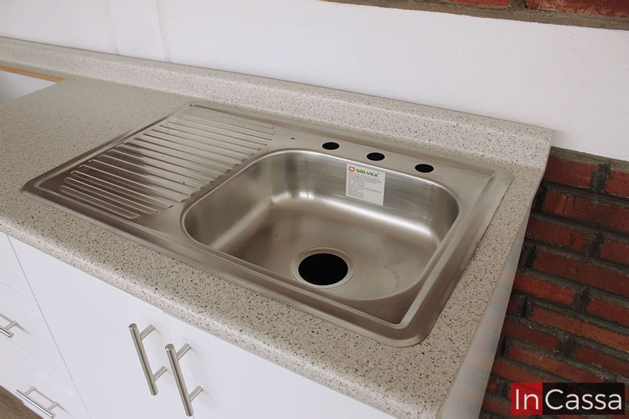 En esta toma se destaca la tarja incluida en el módulo inferior, la cuál es de acero inoxidable y cuenta con un escurridor a la izquierda de la tina. La foto además permite dar un pequeño vistazo a la cubierta de formica de estilo granito de arena.