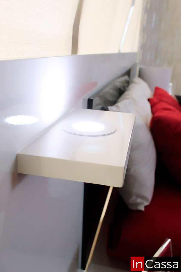 Detalle de la cabecera de cama con iluminación LED integrada y pequeña repisa blanca. Diseño moderno y funcional, ideal para añadir luz ambiental y espacio adicional en el dormitorio. Combina perfectamente con una decoración contemporánea.