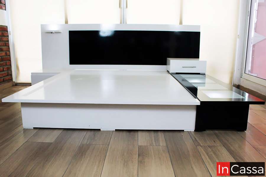 Recamará moderna con base y cabecera en tonos blancos y negros con iluminación LED, diseño minimalista. Incluye burós integrados y una repisa con iluminación LED. Perfecta para un dormitorio elegante y contemporáneo, ofreciendo funcionalidad y estilo.