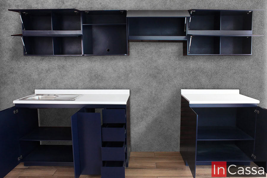Una toma frontal muestra todos los módulos superiores e inferiores completamente abiertos, revelando su capacidad de almacenaje. Se aprecian estantes amplios, puertas elevables con pistón, especiero deslizable y cajones funcionales, todo en elegante MDF azul rey con cubiertas de formaica en estilo blanco fresh.