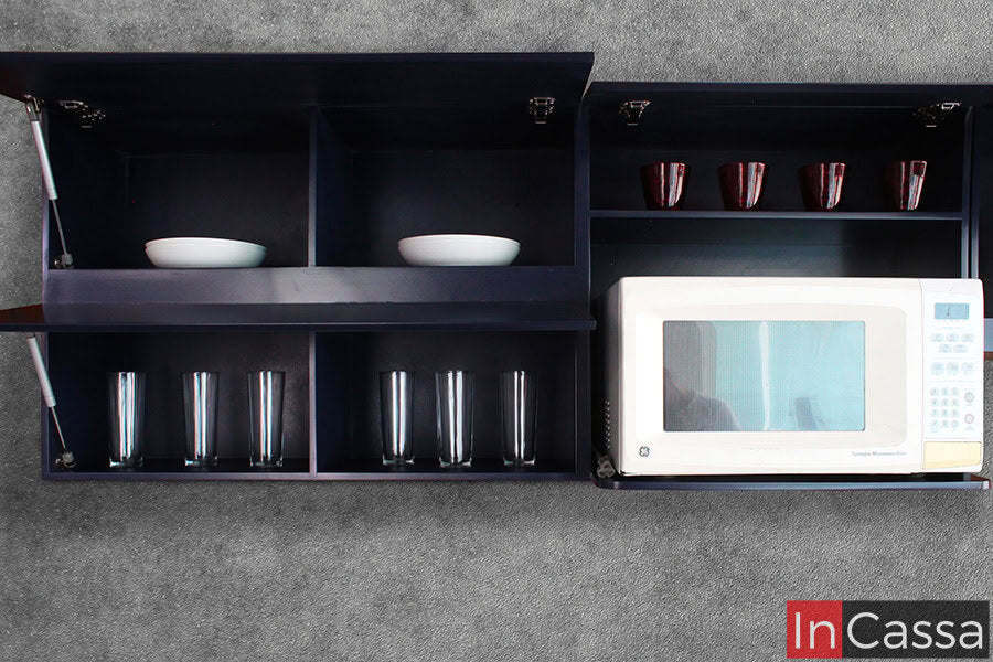 Una toma centrada de la alacena superior izquierda revela un diseño práctico dividido en compartimentos. Los estantes superiores cuentan con puertas elevables mediante pistón neumático, donde se almacenan platos y tazas, mientras que los compartimentos inferiores, son ideales para vasos de uso diario. Todo en un elegante color azul rey con líneas rectas y modernas.