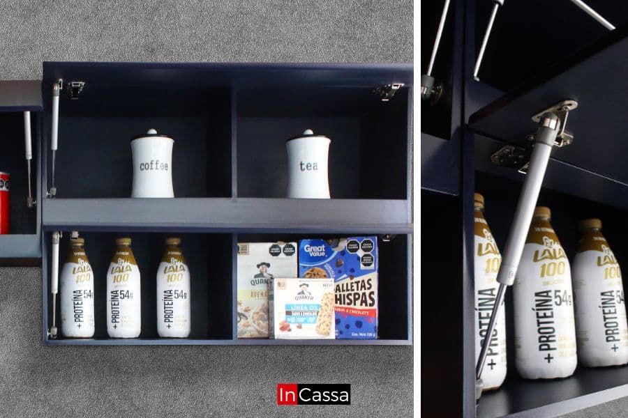 La imagen muestra un módulo superior dividido en cuatro compartimentos, con estantes abiertos y puertas elevables sujetas con pistón neumático. Se destacan los frascos decorativos para café y té, así como un espacio organizado para botellas y cajas de cereales. El acabado azul rey profundo realza su estilo moderno y funcional.