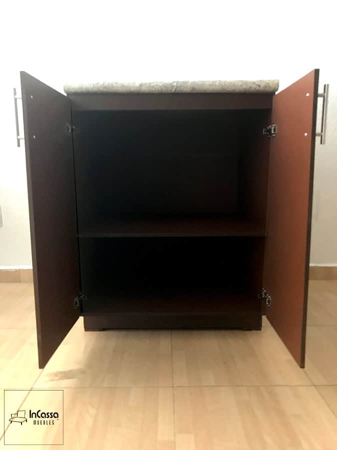 Se presenta un módulo inferior visto de frente con ambas puertas abiertas, revelando su compartimento dividido por un entrepaño. La cubierta de formaica tipo mármol resalta sobre el cuerpo en tono tabaco.