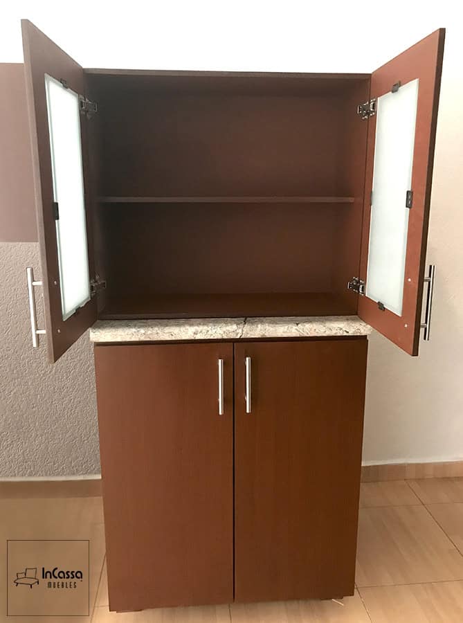 Una toma de frente muestra el módulo lateral derecho en color tabaco con puertas superiores abiertas, que incluyen paneles de cristal esmerilado y jaladeras metálicas. En el interior, se aprecia un entrepaño que optimiza el espacio vertical para una mejor organización de vajilla o despensa.