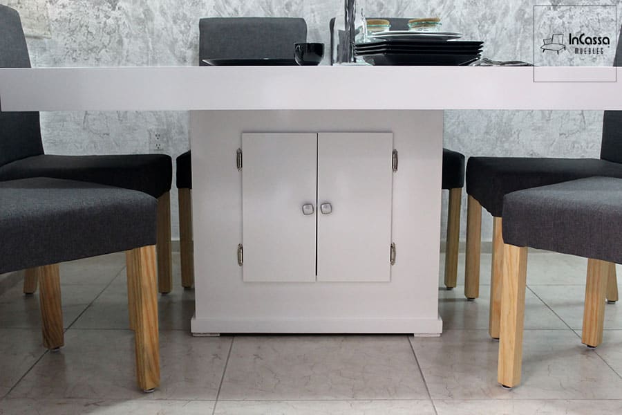 En esta imagen, el enfoque está en la base de la mesa del comedor, que incluye un práctico compartimento de almacenamiento con puertas dobles. Este diseño no solo aporta estabilidad, sino que también ofrece un espacio funcional para guardar utensilios u otros objetos, manteniendo el área ordenada y elegante.