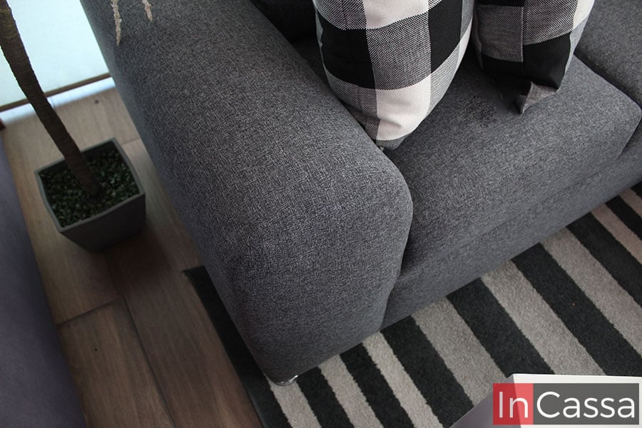 Una toma superior del love seat de la sala, en la que se puede apreciar de mejor manera su descasa brazos y sus asientos, todos tapizados en tela lino mouse al igual que la base de la sala.