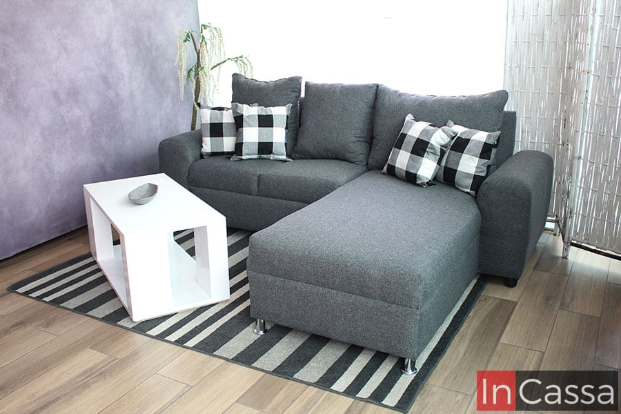 Se muestra la sala en escuadra desde una toma lateral, la cuál resalta el largo del chaise long de la sala y muestra más detalladamente la estructura completa del mueble, tapizado enteramente en tela lino color mouse.